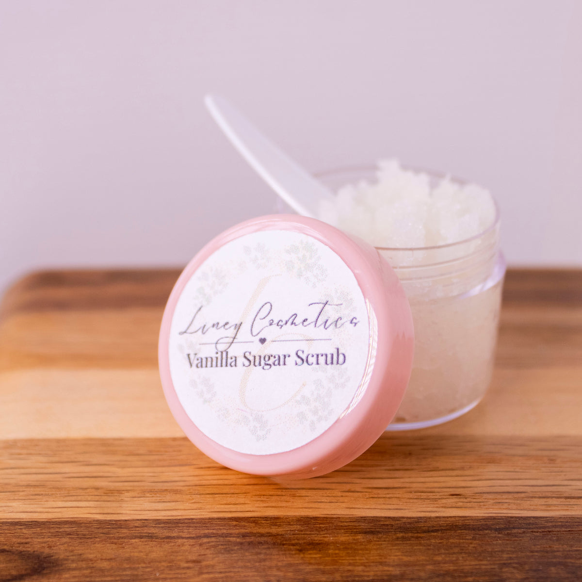 A small jar of Liney Cosmetics Vanilla Lip Scrub with a small spoon sitting in the jar.